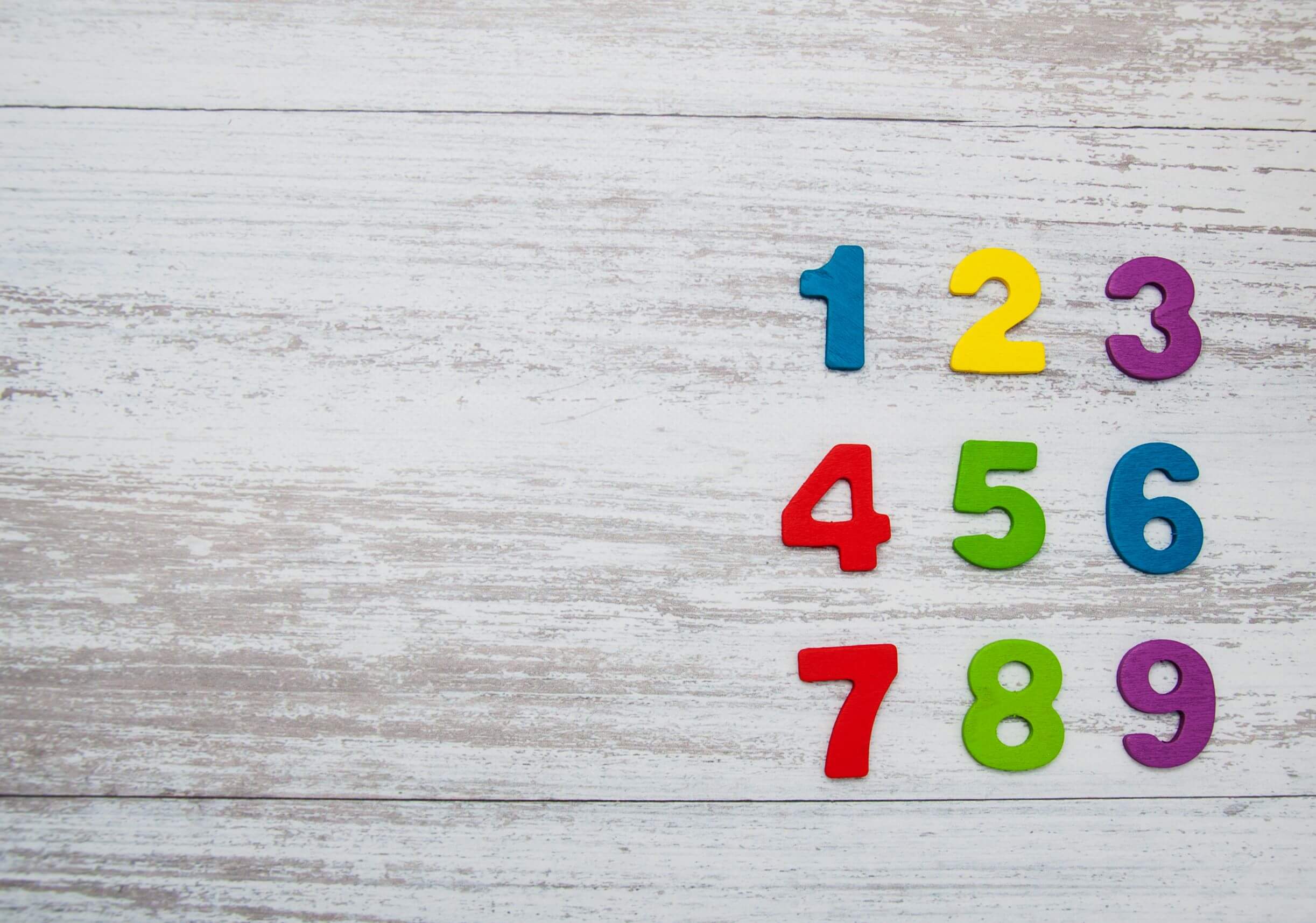 Color numbers 1-9 on light wood background (writing numbers, number or words, when to spell out numbers)